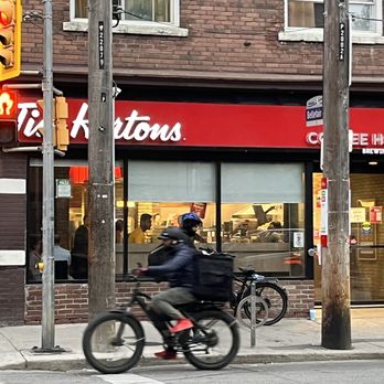 Tim Hortons - a man riding a bike down the street - Bakeries Near Me - Toronto, Ontario