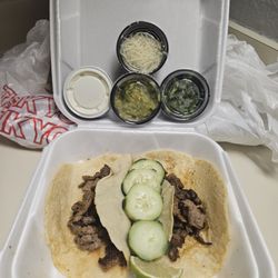 Two carne asada tacos with cucumbers