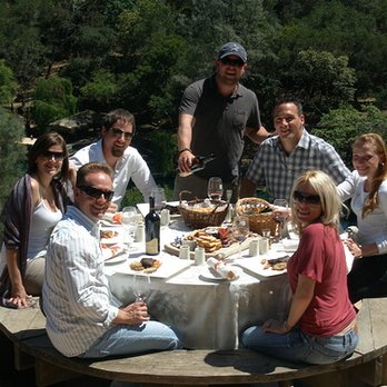 Happy Napa - a group of people sitting around a table - Wine Tours Near Me Happy Napa - a group of people sitting around a table - Wine Tours Near Me