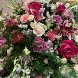 Floral Spray - A vibrant floral arrangement with roses, lilies, and various flowers in shades of pink, purple, white, and red, accompanied by green foliage.
