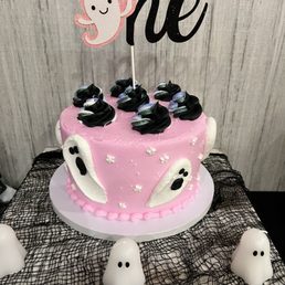 a pink cake with ghost decorations