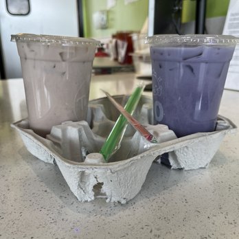 Tastea - Taro Milk Tea in the left hand Ube Milk Tea in the right hand - Bubble Tea Near Me - Long Beach, California Tastea - Taro Milk Tea in the left hand Ube Milk Tea in the right hand - Bubble Tea Near Me - Long Beach, California
