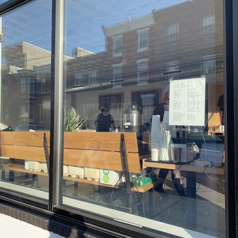Reanimator Coffee - a man sitting on a bench in front of a coffee shop - Coffee & Tea Near Me - Philadelphia, Pennsylvania