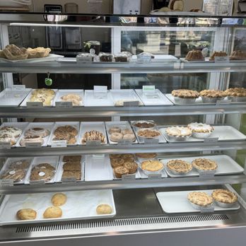 Apple-licious - Oh my goodness!  This is full of yumminess! We purchased an Apple Streusel and a few of the kolaches. - A glass display case showcases a variety of baked goods, including apple pastries, pies, and cookies, in a bakery setting. - Bakeries Near Me - Spring, Texas