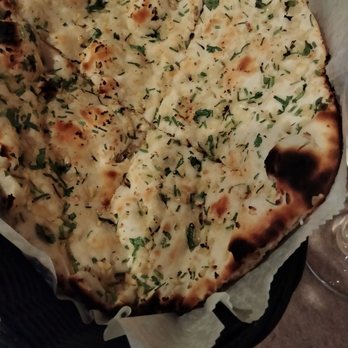 Masala - Garlic naan - A basket contains garlic naan bread topped with chopped herbs, likely served at an Indian restaurant. - Pakistani Near Me - West Warwick, Rhode Island