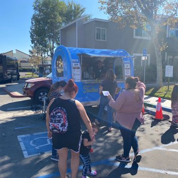 Tastee Flavors - a group of people standing around a food truck - Food Trucks Near Me