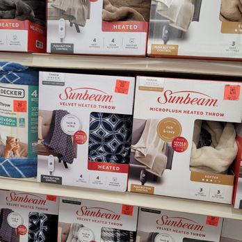 Ollie's Bargain Outlet - Heated blankets, love them - The image shows multiple boxes of Sunbeam heated throws and microplush heated throws arranged on store shelves. The packaging highlights features such as heat settings, auto-off, and machine washability. Some boxes display images of the throws, with labels indicating they are heated and designed for comfort. The products are organized in a retail setting, with visible price tags and product descriptions. - Discount Store Near Me - Barkhamsted, Connecticut