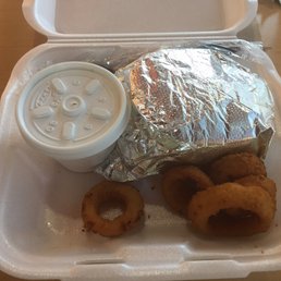 a sandwich and onion rings in a styrofoam container a sandwich and onion rings in a styrofoam container