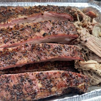 Code 1 BBQ - Ribs and pulled pork - Smoked barbecue ribs with a seasoned crust and pulled pork are presented in a foil container, highlighting a meat-focused dish from a barbecue restaurant. - Caterers Near Me - Wilmington, Massachusetts