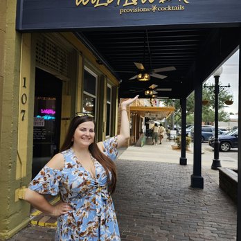 The Wildflower - a woman in a blue dress standing in front of a store - Cocktail Bars Near Me - Sanford, Florida