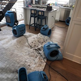 Water Damage Repair Tech - Water Damage Repair Tech setting up air blowers and moisture extraction machines in the kitchen. - Damage Restoration Near Me - Georgetown, Texas