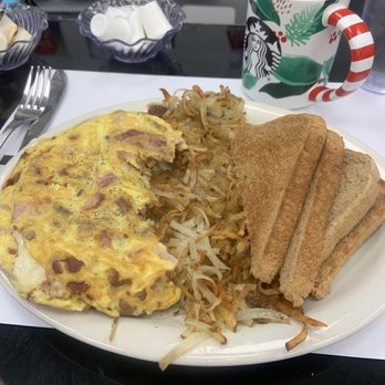 Muffins - Meat Lovers Omelette with hash browns and wheat toast. - A breakfast plate features an omelet, hash browns, and toasted bread slices, with a holiday-themed mug nearby, on a diner table. - American Near Me - Bridgeport, Pennsylvania