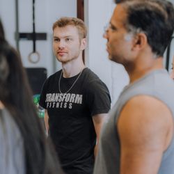 Transform Fitness - coach explains the workout as members listen intently.