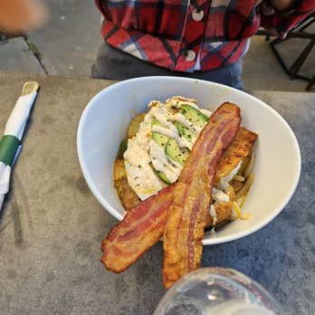 Cajun Breakfast Joint - A bowl containing bacon, avocado slices, and other ingredients, placed on a table with a fork wrapped in a napkin nearby. - Breakfast & Brunch Near Me - Phoenix, Arizona