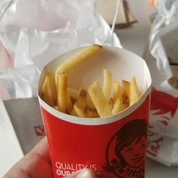 a hand holding a cup of french fries a hand holding a cup of french fries