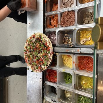 The Pizza Press - a person putting toppings on a pizza - Pizza Near Me - Anaheim, California The Pizza Press - a person putting toppings on a pizza - Pizza Near Me - Anaheim, California
