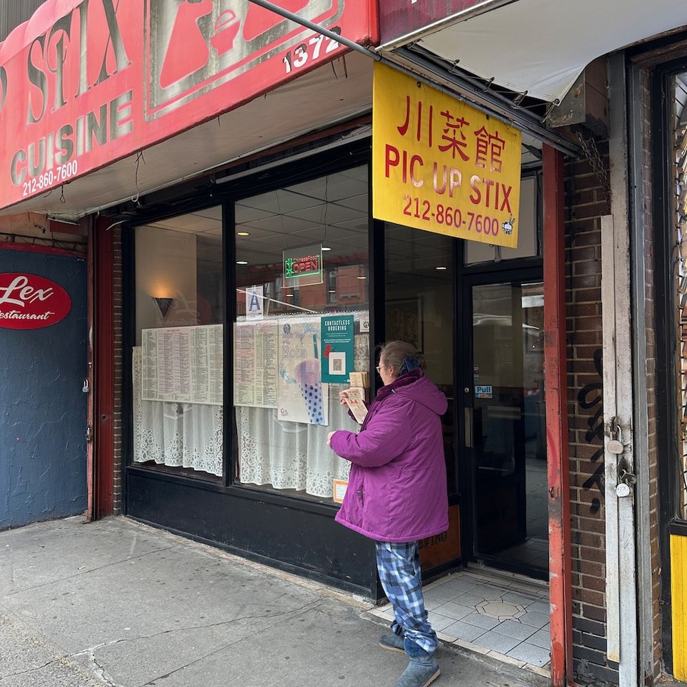 a woman taking a picture of a storefront a woman taking a picture of a storefront