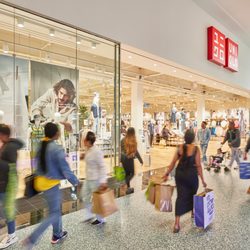 Shoppers carrying bags walk past UNIQLO inside Green Acres Mall.