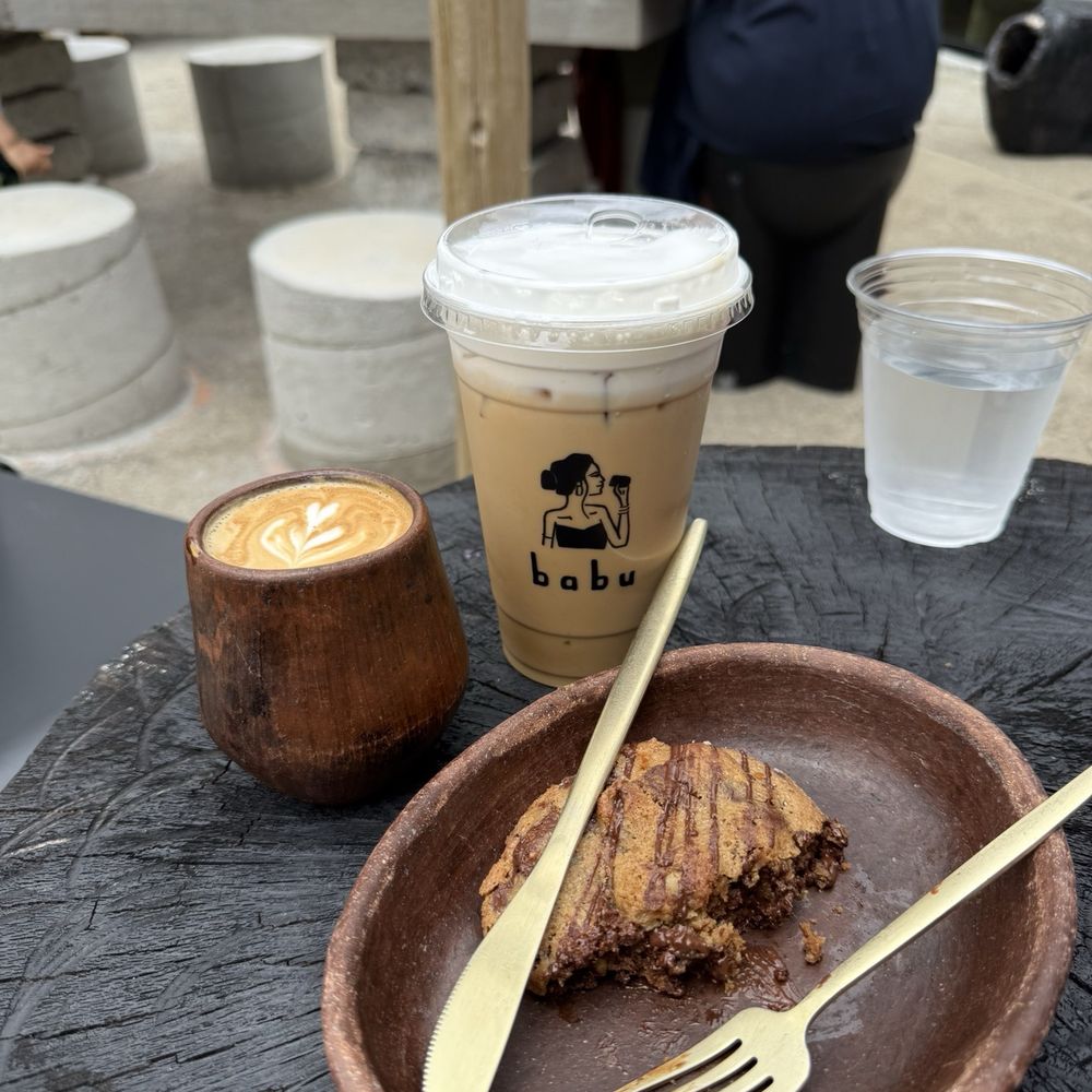 Cafe Babu - Iced latte w cold foam and half eaten spiced chocolate cookie - Coffee & Tea Near Me - Nashville, Tennessee Cafe Babu - Iced latte w cold foam and half eaten spiced chocolate cookie - Coffee & Tea Near Me - Nashville, Tennessee