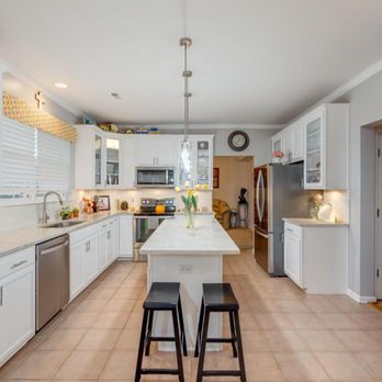 Sam's Remodeling - a kitchen with white cabinets and a large island - General Contractors Near Me