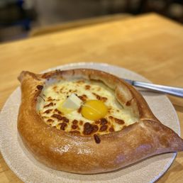 $26 Khachapuri Adjaruli | Boat-shaped cheese bread with butter and an egg. $26 Khachapuri Adjaruli | Boat-shaped cheese bread with butter and an egg.