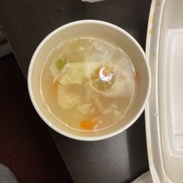 a bowl of soup and a styrofoam container a bowl of soup and a styrofoam container