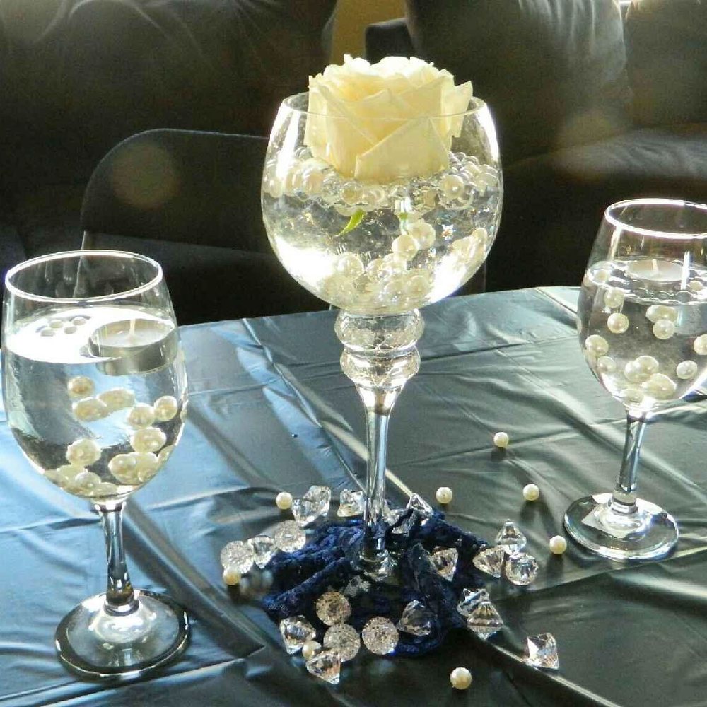 A Golden Affair - A few wine glasses filled with some pearls, candles and a rose in the middle. With diamonds and lace accenting the middle of the table. - Party & Event Planning Near Me A Golden Affair - A few wine glasses filled with some pearls, candles and a rose in the middle. With diamonds and lace accenting the middle of the table. - Party & Event Planning Near Me