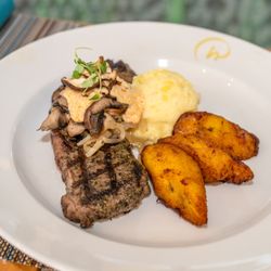Chimichurri marinated Grilled New York Steak with sauteed mushrooms, onions, gorgonzola sauce, mashed potatoes, sweet plantains