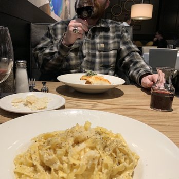 Gratzi - a man sitting at a table with a plate of pasta and a glass of wine - Italian Near Me - Midland, Michigan Gratzi - a man sitting at a table with a plate of pasta and a glass of wine - Italian Near Me - Midland, Michigan