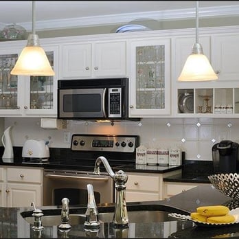 Genesis Construction - a kitchen with white cabinets and black countertops - General Contractors Near Me Genesis Construction - a kitchen with white cabinets and black countertops - General Contractors Near Me