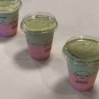 MOTW - Strawberry Matcha waiting for their owners - Three layered beverages in clear plastic cups with lids, featuring pink, green, and clear layers, placed on a white table. - Desserts Near Me - Avon, Indiana