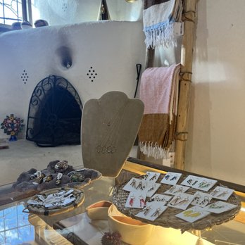Luna and Luz - Jewelry and accessories are arranged on display trays and a necklace stand in a boutique shop, with towels hanging on a wooden rack in the background. - Jewelry Near Me - Albuquerque, New Mexico