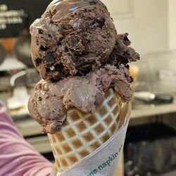 Close-up of Waffle Cone with two scoops of ice cream: Blue Cow Patty and Dark Chocolate and Raspberry.