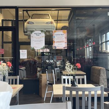 Chick-fil-A - The Playground - A restaurant or cafe interior with tables, chairs, and floral decorations, seen through a glass partition. Posters advertising events are visible. - Fast Food Near Me - Clinton, Maryland