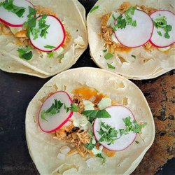 JazJay Eats - Braised Chipotle chicken, guacamole cream, radish, onions, and cilantro on a corn tortilla.