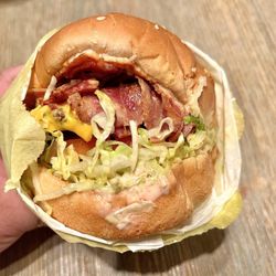 The Lucky Greek - Lucky Burger Pastrami Cheeseburger. Thinly sliced, smoky pastrami over a juicy beef patty. It's got all the fixins in it.