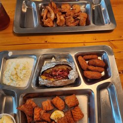 Boondocks Fish Camp & Smoke House - Ou     Bottom is lemon pepper salmon bites with slaw and a loaded baked potato.  Top is butterflied shrimp with grits.