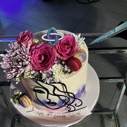 Custom cake from J&D cakes  with TXT album cover art symbol, fresh flowers and macaroons