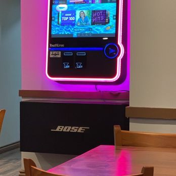 Mint Kitchen & Bar - a table with chairs and a television - Vietnamese Near Me - Worcester, Massachusetts