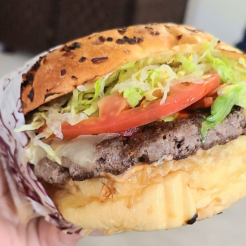 a hand holding a hamburger a hand holding a hamburger