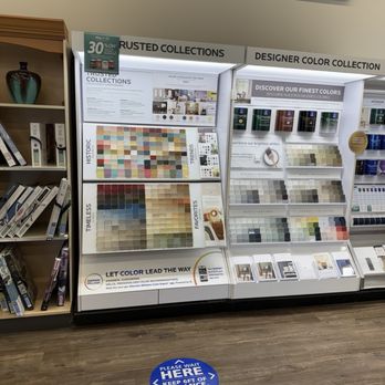 Sherwin-Williams Paint Store - A display stand at Sherwin-Williams Paint Store in Olathe, KS, showcases various paint color samples organized into categories such as historic, timeless, trends, favorites, and more. The stand includes informational signage about color collections and recommendations, with a promotional sign offering 30% off. The store floor features a blue social distancing marker that reads 'Please wait here, keep off of distance, thank you.' The background includes part of the store interior and additional display shelves. - Paint Stores Near Me - Olathe, Kansas