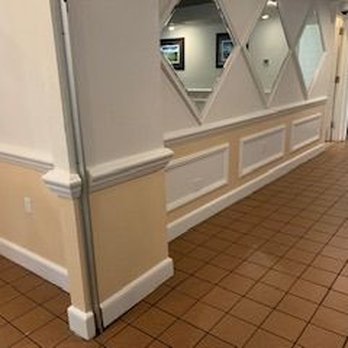 Dean Painting - A hallway features light peach-colored lower walls with white wainscoting, diamond-shaped mirrors above, and brown tiled floo... - Painters Near Me - Venice, Florida Dean Painting - A hallway features light peach-colored lower walls with white wainscoting, diamond-shaped mirrors above, and brown tiled floo... - Painters Near Me - Venice, Florida