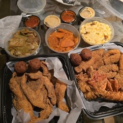 Wally's NW Soul - Catfish dinner on the left and seafood special on the right. Fried cabbage, candied yams, and Mac n cheese at top with condiments.