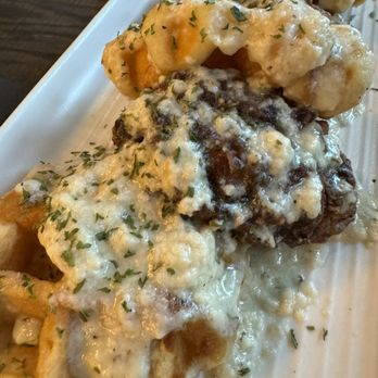Brick + Mortar - Chicken and waffles - A dish featuring chicken and waffles topped with melted cheese and sprinkled with herbs, served on a white plate. - Bars Near Me - Pittsburg, Kansas