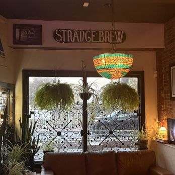 Jerome's - Looking out the front window - A cafe interior features hanging ferns, potted plants, a stained glass ceiling lamp, and a leather sofa near a window with decorative ironwork. - Sports Bars Near Me - Portland, Maine