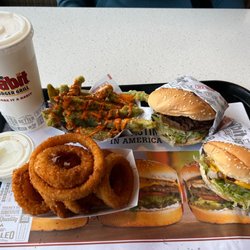 Habit Burger & Grill - Two original charburger's with onion rings and tempura green beans with sriracha sauce drizzled on top.