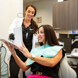 Grand Family Dentistry - Dr. Bratcher and a patient pictured admiring her new smile.