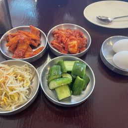 Banchan (side dishes of fish cake, kimchi, cucumbers soaked in rice vinegar, bean sprouts, and egg to crack into tofu stew) Banchan (side dishes of fish cake, kimchi, cucumbers soaked in rice vinegar, bean sprouts, and egg to crack into tofu stew)