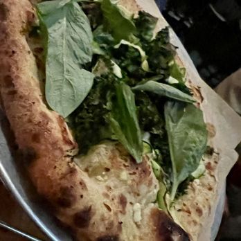 Sofia - Verde pizza - A pizza with a thick crust topped with fresh leafy greens, served on a metal tray with parchment paper. - Italian Near Me - New Orleans, Louisiana