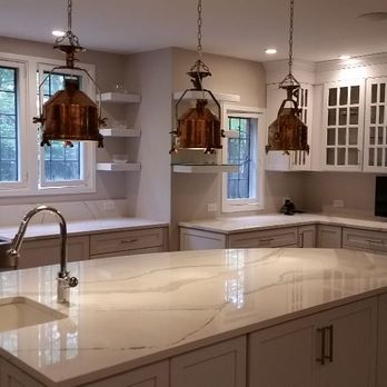 Carmel Construction Co - a kitchen with white cabinets and marble countertops - General Contractors Near Me